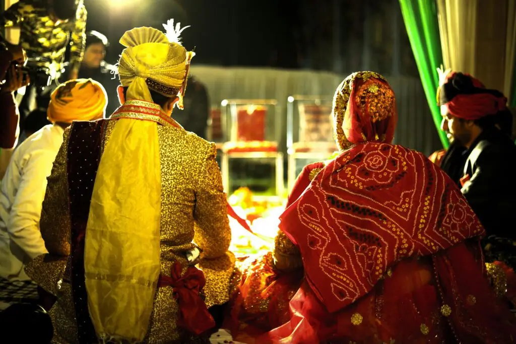 Colorful Indian bride and groom at a traditional wedding ceremony during the night.